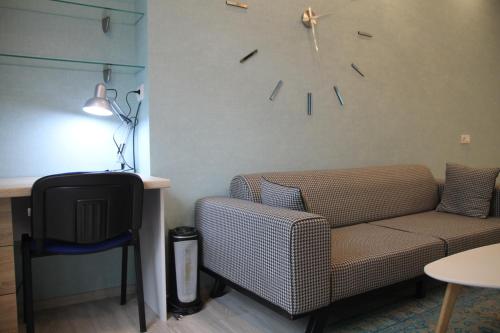 a living room with a couch and a clock on the wall at Cozy apartment in Vake in Tbilisi City