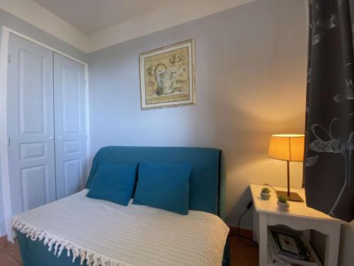 une chambre avec une tête de lit bleue et un lit dans l'établissement Les Issambres: Studio cabine 4 couchages, clim, piscine, parking - FR-1-226-84, aux Issambres