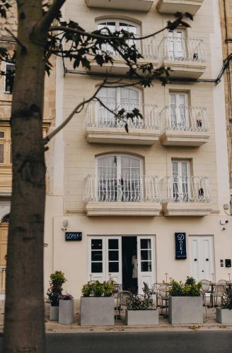a white building with balconies and tables and chairs at Dock 1 Boutique Hotel in Cospicua