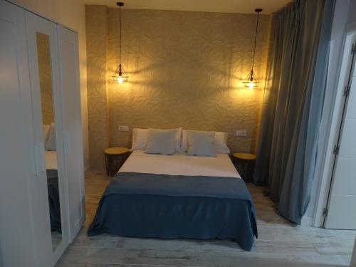 sypialnia z łóżkiem z dwoma światłami na ścianie w obiekcie Casasjerezanas Loft Aitana w mieście Jerez de la Frontera
