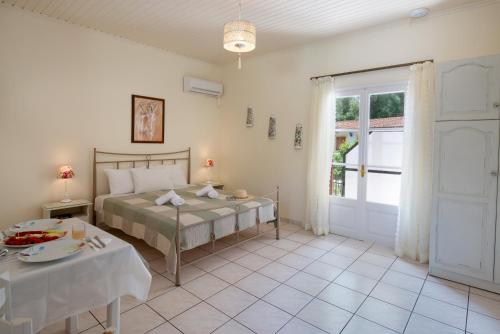 a bedroom with a bed and a table and a door at LIvadi Studios with Pool in Lákka