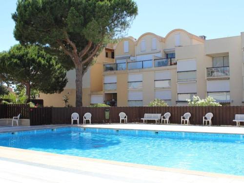 une piscine avec des chaises et un bâtiment dans l'établissement Studio à Gruissan, 2 couchages, piscine, proche plage et commerces - FR-1-229-106, à Gruissan