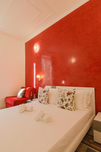 a bedroom with a white bed with a red wall at Erreggi Luxury Rooms in Rome