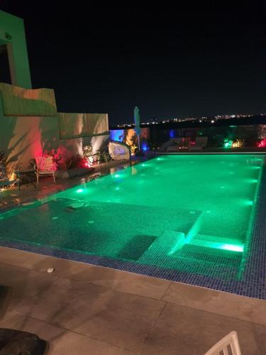 a swimming pool at night with lights on at צדפת המדבר in Giv'ot Bar