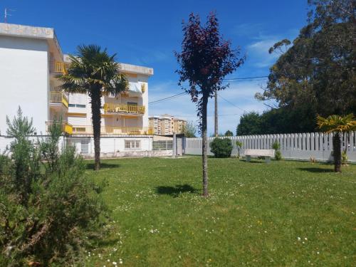 a yard with two palm trees and a white fence at Oriñon Beach Apartment in Oriñón