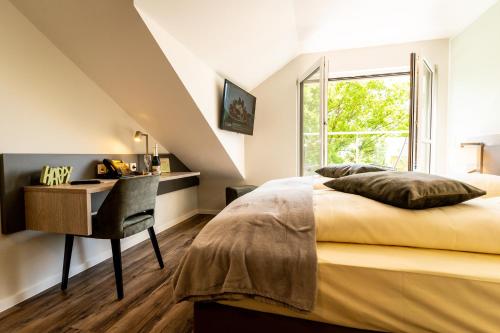Schlafzimmer mit einem Schreibtisch, einem Bett und einem Fenster in der Unterkunft Hotel Landhaus Silbertanne in Rotenburg an der Fulda