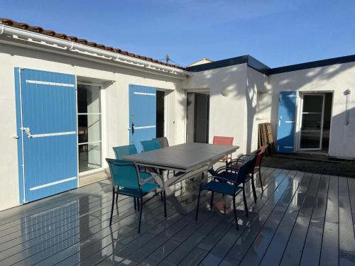 une terrasse en bois avec une table et des chaises dans l'établissement Maison rénovée tout confort - Proche plage, commerces et animations - WIFI inclus - FR-1-231-76, à Bretignolles-sur-Mer