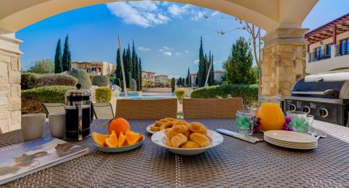 uma mesa com pratos de comida por cima em Pool side ground floor apartment BF02 - Theseus Village, Aphrodite Hills Resort em Kouklia