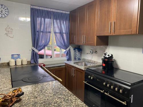 a kitchen with a black stove and a sink at Casa Taboada Ribeira Sacra in Vilelos