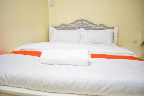 Cama blanca con sábanas y almohadas rojas y blancas en Luna Light Guest House en Naivasha
