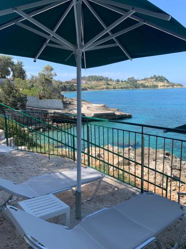 a pair of chairs under an umbrella on the beach at Studios Angeliki in Lassi