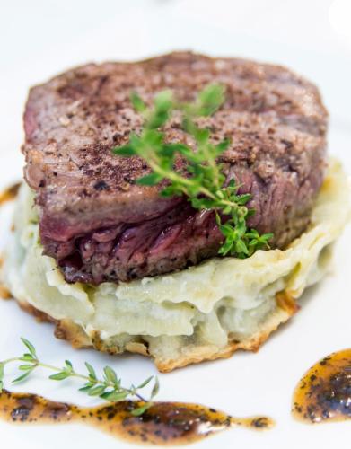 a piece of meat on a white plate with a plant on it at La Capitelle in Mirmande