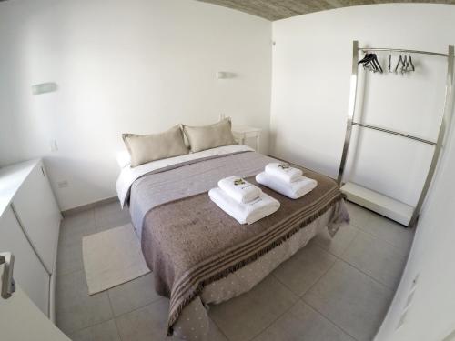 1 dormitorio con 1 cama con 2 toallas en Departamentos Las Tablas en Puerto Madryn