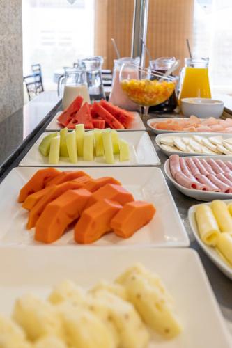 a table topped with plates of different types of food at Hotel Plaza Norte in Joinville