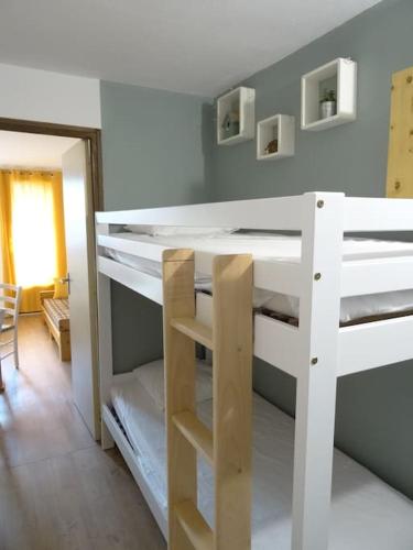 Ce lit superposé blanc se trouve dans un dortoir. dans l'établissement Appartement au cœur du village avec parking privé, à Mijoux