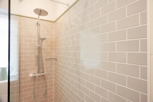 a shower in a bathroom with pink tiles at Embankment Hotel in Bedford