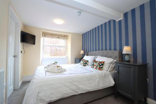 a bedroom with a large bed with blue striped walls at The Little Lion Inn, Red Lion in Wellingore