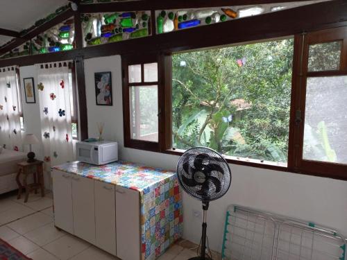 uma cozinha com ventoinha num quarto com janelas em Loft dos Vagalumes em Boiçucanga