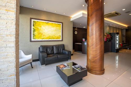 a living room with a couch and a painting on the wall at Hotel Plaza Norte in Joinville