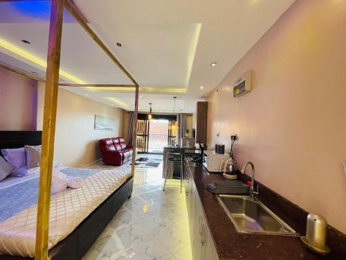 a room with a bed and a kitchen with a sink at Trendy apartments in Entebbe