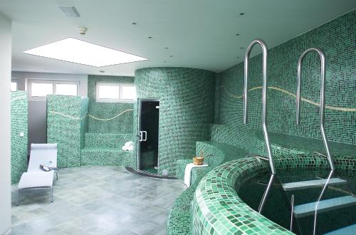 a bathroom with green tiled walls and a bath tub at Seiser Alm Plaza in Alpe di Siusi