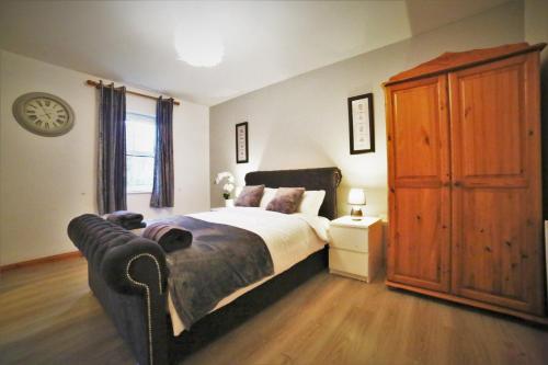 恩尼斯基林的住宿－Fermanagh Home，一间卧室配有一张大床和一个木制橱柜