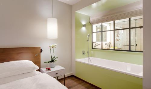 a bedroom with a tub and a bed and a window at Giardino Ascona in Ascona