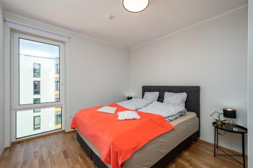 1 dormitorio con 1 cama con manta naranja en CITYGATE APARTMENT WITH SUN BALCONY, en Tartu
