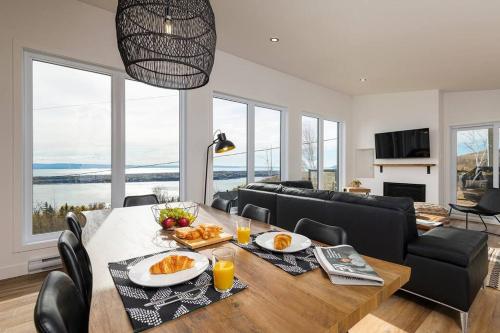 a dining room with a table with food on it at Le Charmant- Magnifique vue sur le fleuve et spa in Saint-Joseph-de-la-Rive