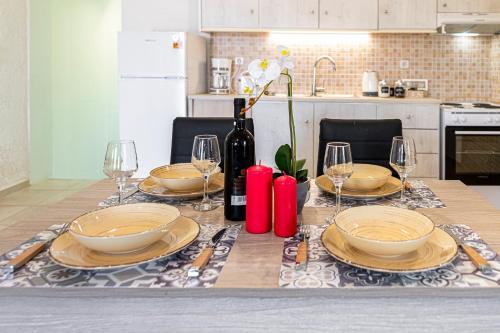 einen Tisch mit Tellern und Gläsern sowie eine Flasche Wein in der Unterkunft Doukas House Cottage with vineyard, Artemis in Artemida