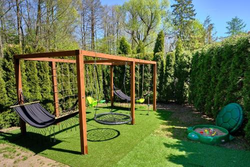 a swing set in a yard with two chairs at Czarny Kot Mazury Dom Całoroczny in Małkinie