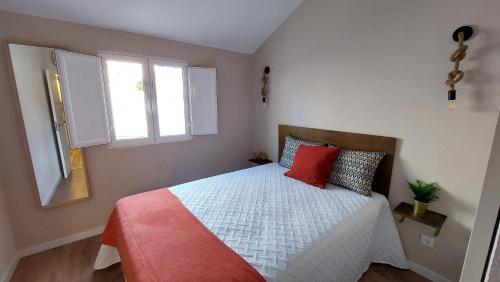 a bedroom with a bed with red pillows and a window at Airport house in Faro