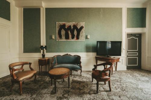 a living room with chairs and a tv and a couch at Logis Hôtels Château de La Barge in Chaintré