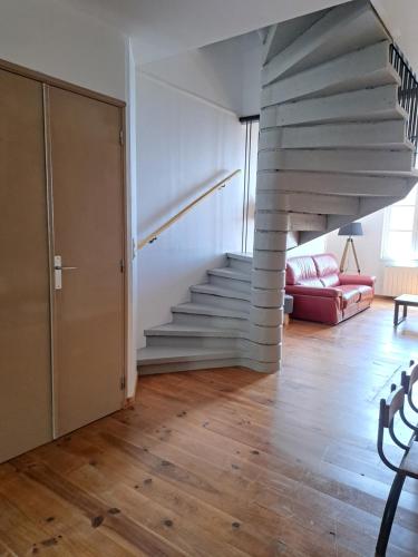 a staircase in a living room with a red couch at Maison de charme spacieuse, terrasse et vue sur la place in Monflanquin