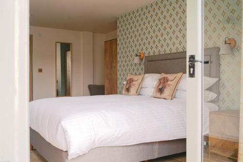 a bedroom with a large bed with white sheets at The Blind Bull in Little Hucklow