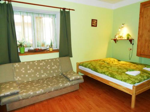 a bedroom with a bed and a couch and a window at Apartmány Johanka in Náchod