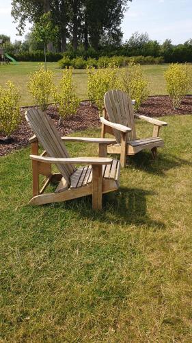 two wooden benches sitting on the grass in a field at B&B 't Meesterhof in Deinze