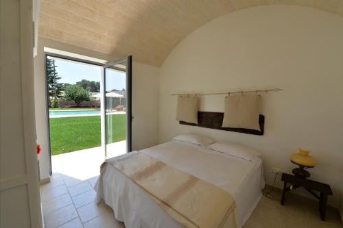 Un dormitorio con una cama y una puerta corrediza de vidrio. en Masseria Il Mandorlo Fiorito x 8 Piscina Privata, en Ceglie Messapica
