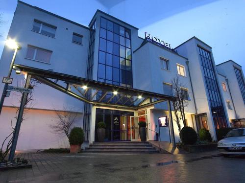 a building with a entrance with a car parked in front at Hotel Am Park in Leinfelden-Echterdingen