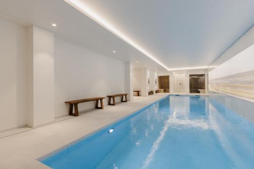 a large swimming pool with blue water in a building at Portwin luxury stays in Knokke-Heist