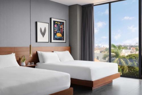 two beds in a hotel room with a large window at MARQUEE Playa Hotel in Playa del Carmen