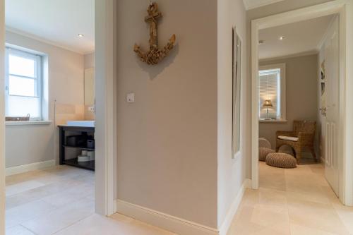 un couloir d'une maison avec une horloge sur le mur dans l'établissement Reetdachhaus Dreilanden Reetdachhaus Sünn Hart, à Sankt Peter-Ording