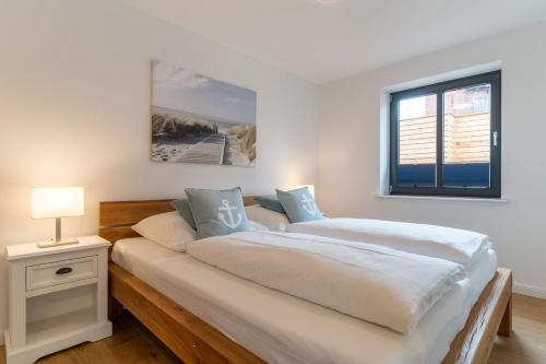 een witte slaapkamer met een groot bed en een raam bij Appartement Kattrepel Appartement Kattstern in Sankt Peter-Ording