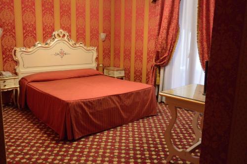 a bedroom with a bed with a red and white bedspread at Hotel Belle Arti in Venice