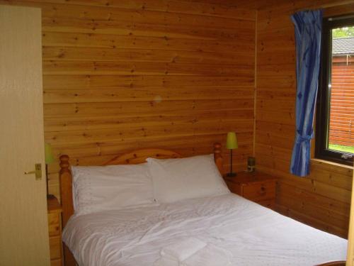 a bedroom with a bed with a wooden wall at Loch Lomond Lodge in Rowardennan