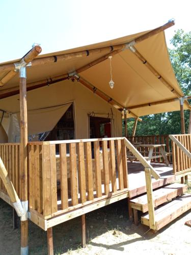 een tent met een luifel en een houten veranda bij Gîte et lodges du Hitton in Biran