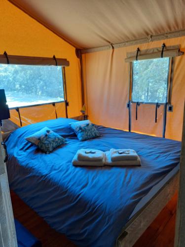 a bed in a tent with two towels on it at Hitton Séjours Nature in Biran