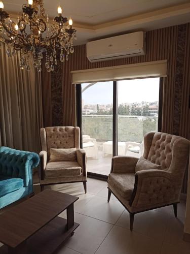 a living room with two chairs and a chandelier at AlQimah Hotel Apartments in Amman