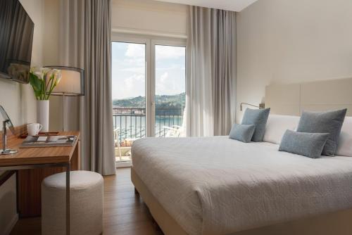 Cette chambre comprend un lit, un bureau et une fenêtre. dans l'établissement Doria Park Hotel, à Lerici