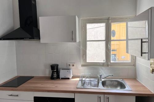 un comptoir de cuisine avec un évier et une fenêtre dans l'établissement Studio avec mezzanine dans le coeur du vieil Antibes wifi climatisation, à Antibes